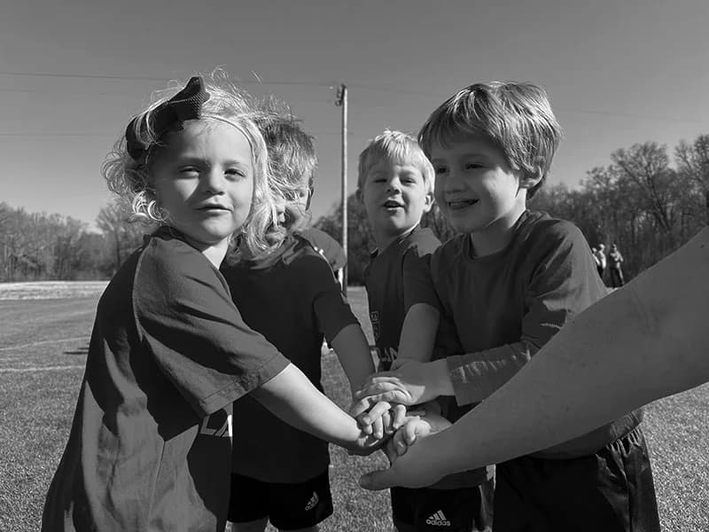 Young recreational players bringing their hands together in a team huddle